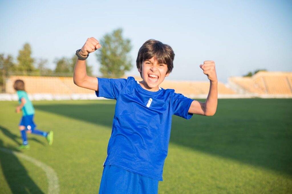 Joyful boy celebrating a soccer win outdoors in Portugal.