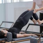 Women engaging in reformer Pilates with assistance in a Shenzhen studio promoting healthy lifestyle.
